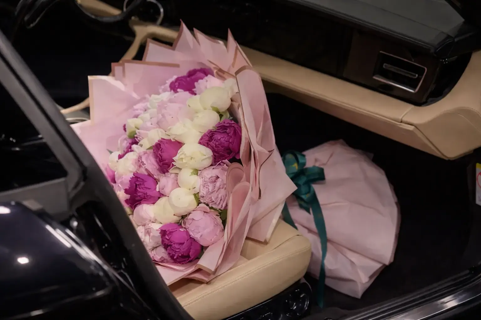 Aracın arka koltuğunda pembe ve beyaz şakayık buketleri